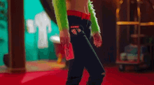 a woman in a green crop top and black jeans is walking on a red carpet