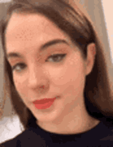 a close up of a woman 's face with red lipstick and a black shirt .