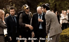 a group of men are standing in a park and one of them is wearing a crown on his head .