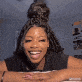 a woman with braids is smiling and laughing while laying on a bed .