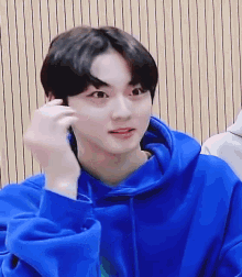 a young boy wearing a blue hoodie is looking at the camera