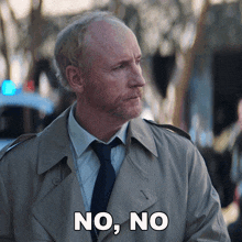 a man in a trench coat and tie is saying no