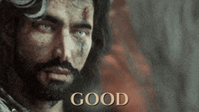 a man with a beard and horns looks at the camera with the word good below him
