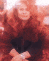 a woman wearing a watch is sitting with her arms crossed .