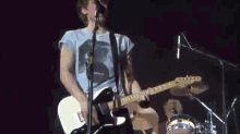 a man is playing a guitar and singing into a microphone while wearing a shirt that says lee