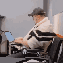 a man wearing a hat and glasses is using a laptop