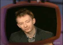 a man in a suit is smiling in front of a television that says adult swim