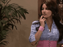 a woman wearing a pink belt and a blue shirt is talking on a cell phone