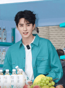 a young man in a blue shirt is holding a bunch of fruit
