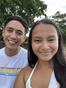 a man and a woman are posing for a picture and the man is wearing a shirt that says hawaii