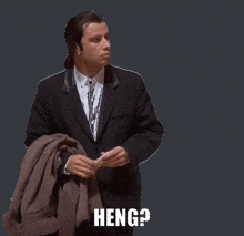 a man in a suit is holding a brown jacket and says " heng "