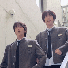 two boys wearing school uniforms and ties are standing next to each other and one has a name tag that says nmnm