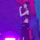 a woman singing into a microphone on a stage with purple lights