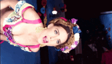 a woman in a colorful dress with flowers in her hair is making a funny face
