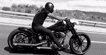 a man wearing a helmet is riding a harley davidson motorcycle on a highway .