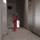 a woman in a red outfit is standing in a hallway next to a door