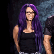 a woman with long purple hair and glasses is wearing a black tank top .