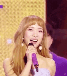 a woman singing into a purple microphone with a star in the corner