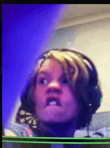 a girl wearing headphones makes a funny face in front of a blue background