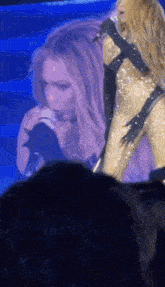 a woman singing into a microphone with a crowd watching