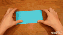 a person is holding a piece of blue paper in their hands .