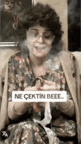 a woman in a floral dress is smoking a cigarette and says ne cektin beee ..