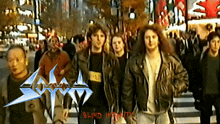 a group of people walking down a street with blind infinity written in red