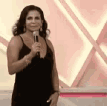 a woman in a black dress is holding a microphone and smiling .