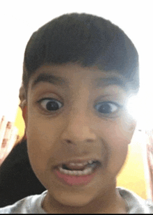 a young boy is making a funny face with his eyes wide open