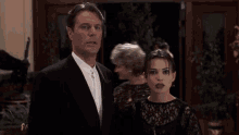 a man in a suit and tie stands next to a woman in a black lace dress