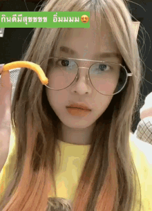 a girl wearing glasses and a yellow shirt is holding an orange