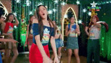 a group of women are dancing on a stage in a room .