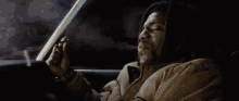a man is smoking a cigarette while sitting in the back seat of a car .