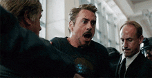 robert downey jr. is being held by a group of men while wearing a black t-shirt .