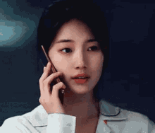 a woman is talking on a cell phone while wearing a white shirt .