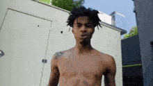 a shirtless man with dreadlocks is standing in front of a white building .
