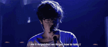 a man singing into a microphone with the words " we 'll forget that we forgot how to talk " behind him