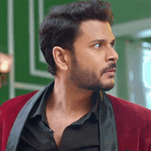 a man with a beard wearing a red jacket and a black shirt