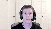 a man wearing headphones and a microphone is sitting in front of a computer .