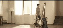 a man in a baseball cap is standing in front of a mirror in a living room .