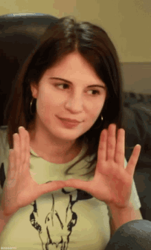 a woman wearing a t-shirt with a skull on it making a heart with her hands