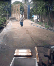 a little boy running down a dirt road with a cardboard box on the ground