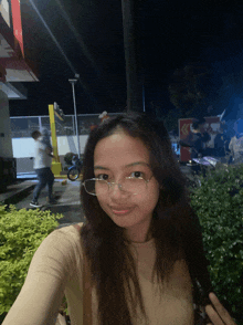 a girl wearing glasses takes a selfie in front of a mcdonalds