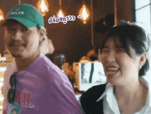 a man and a woman are laughing together in a restaurant . the woman is wearing a rolex hat .