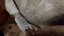 a person is holding a mop in front of a dirty wall