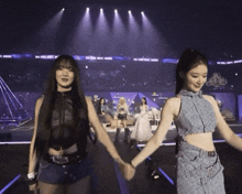 two women hold hands on a stage with a sign that says 2014 global music awards in the background