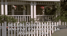a white picket fence surrounds a white house with a porch and flowers on it .