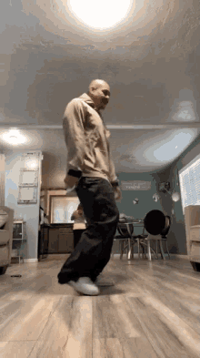 a man is dancing in a living room with a sign on the wall that says ' i love you '