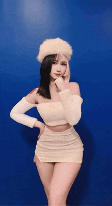 a woman in a white off the shoulder top and skirt stands in front of a blue background