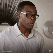a man wearing glasses and a striped shirt has the hashtag #thegoodplace